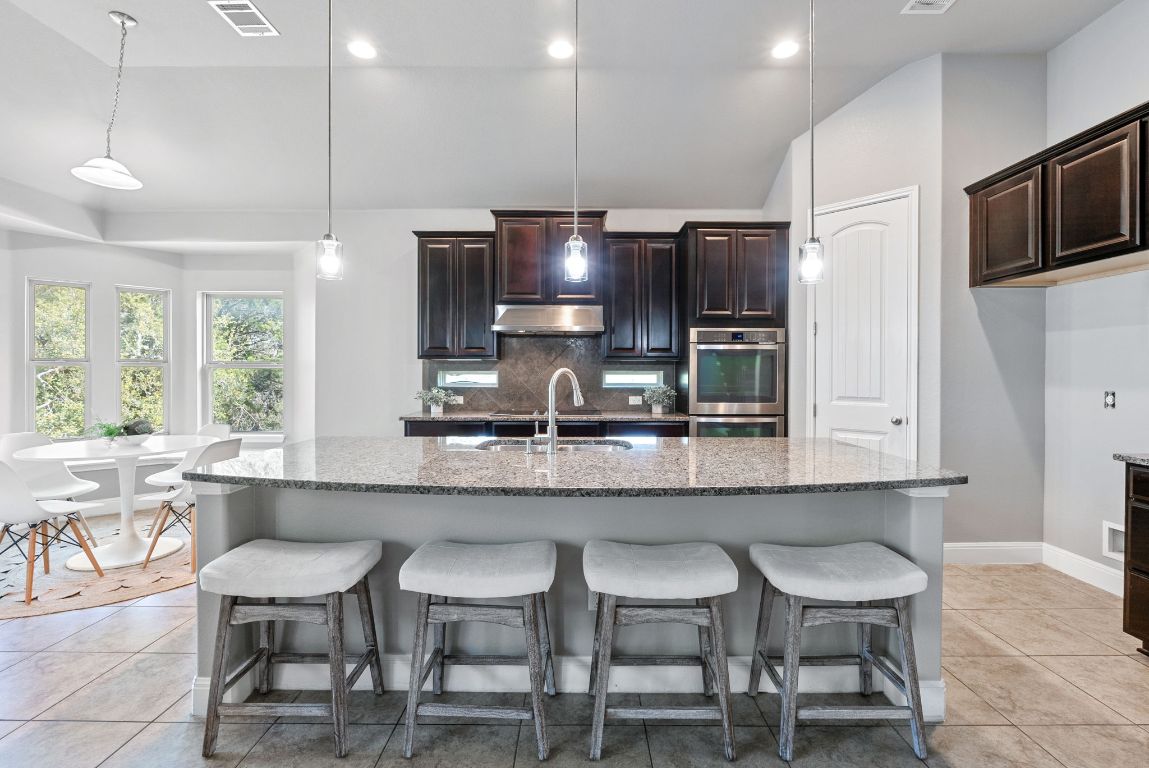 7817 Aria Loop Austin, TX 78736 - Photo 14 of 40 The kitchen has dark cabinetry, granite counters and stainless appliances.