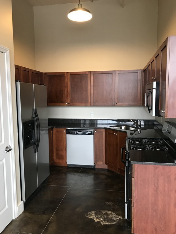 21 Illinois Street, Unit 402 Worcester, MA 01610 - Photo 12 of 16 a kitchen with stainless steel appliances granite countertop a stove a refrigerator and a sink with wooden cabinets