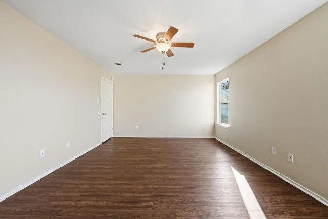 a view of a room with wooden floor and ceiling fan