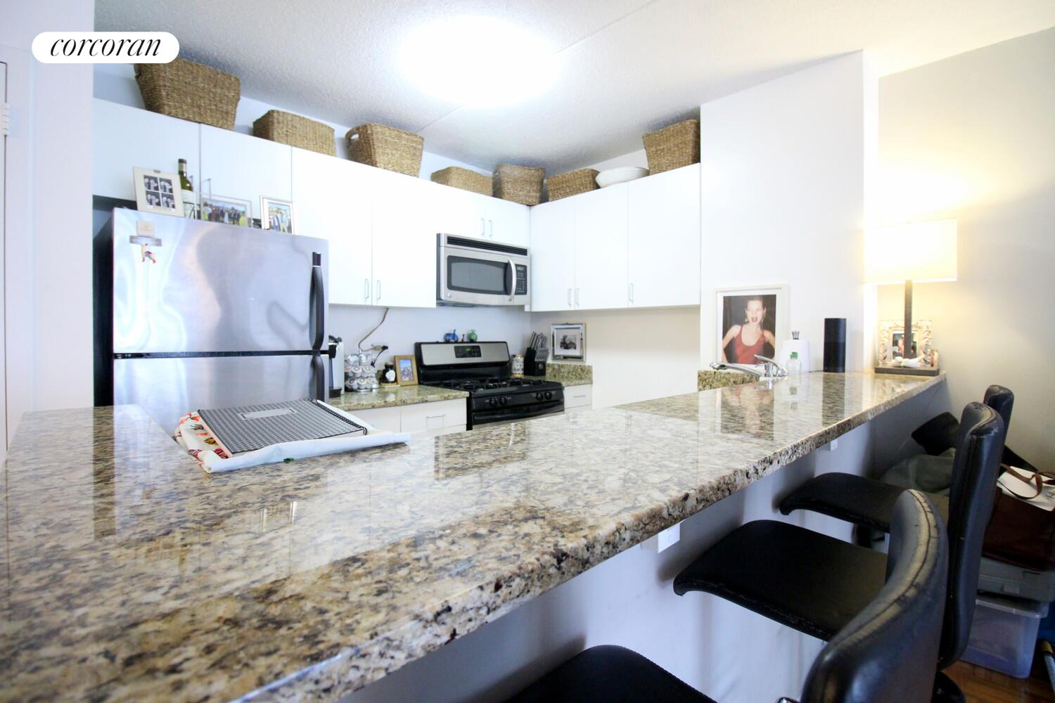 225 8th Avenue, Unit 5E Manhattan, NY 10011 - Photo 4 of 13 a kitchen with granite countertop a table chairs stove and granite counter top