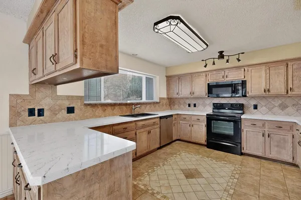 a kitchen with granite countertop a sink stove and cabinets