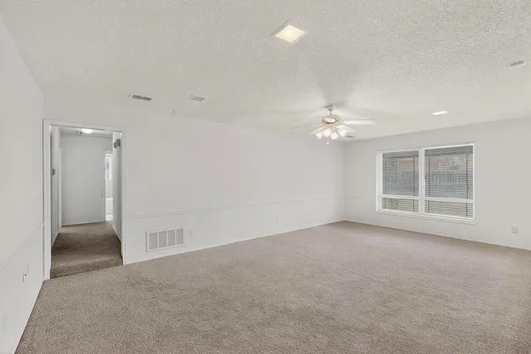 en empty room with windows and ceiling fan
