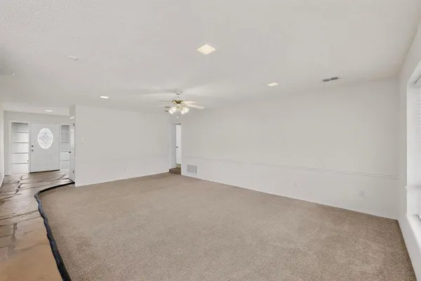 an empty room with a chandelier fan and windows