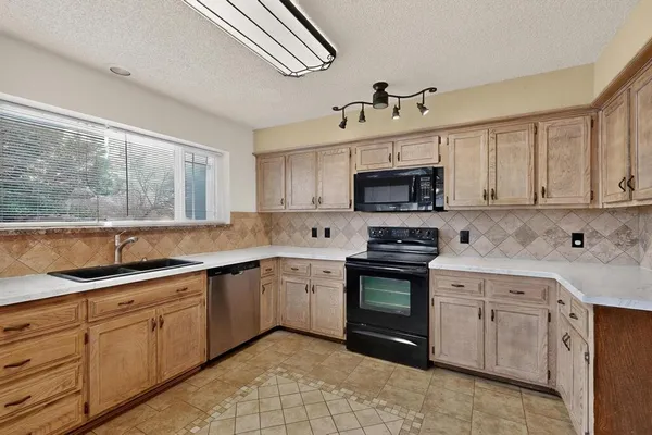 a kitchen with cabinets appliances a sink and a window