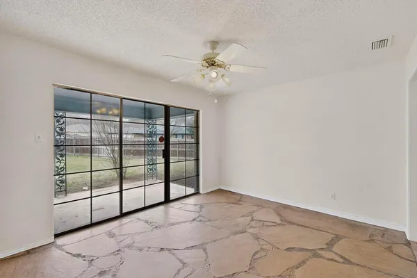 an empty room with windows and ceiling fan