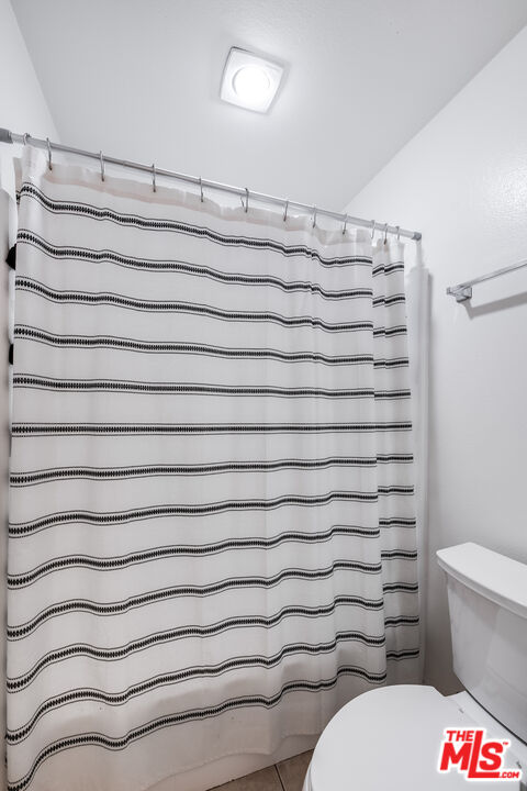 4558 Willis Avenue, Unit 121 Sherman Oaks, CA 91403 - Photo 25 of 34 a bathroom with a toilet and a shower curtain
