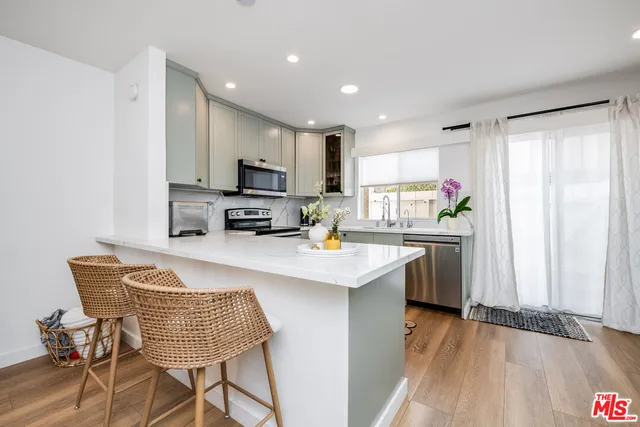 a kitchen with kitchen island granite countertop a stove a sink a microwave a dining table and chairs with wooden floor