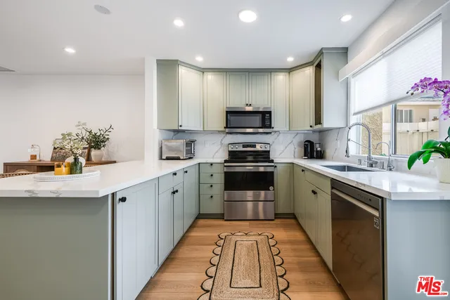 a kitchen with stainless steel appliances a sink dishwasher stove refrigerator and cabinets