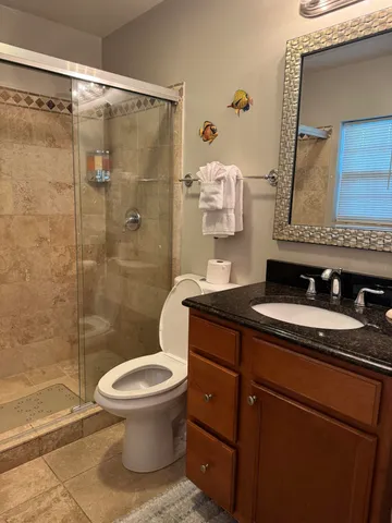 a bathroom with a granite countertop sink toilet and shower
