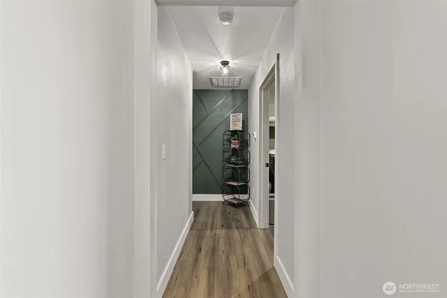 a view of a hallway with wooden floor and a bathroom