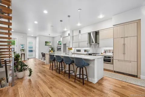 a kitchen with stainless steel appliances granite countertop a refrigerator a stove top oven a sink dishwasher and white cabinets with wooden floor