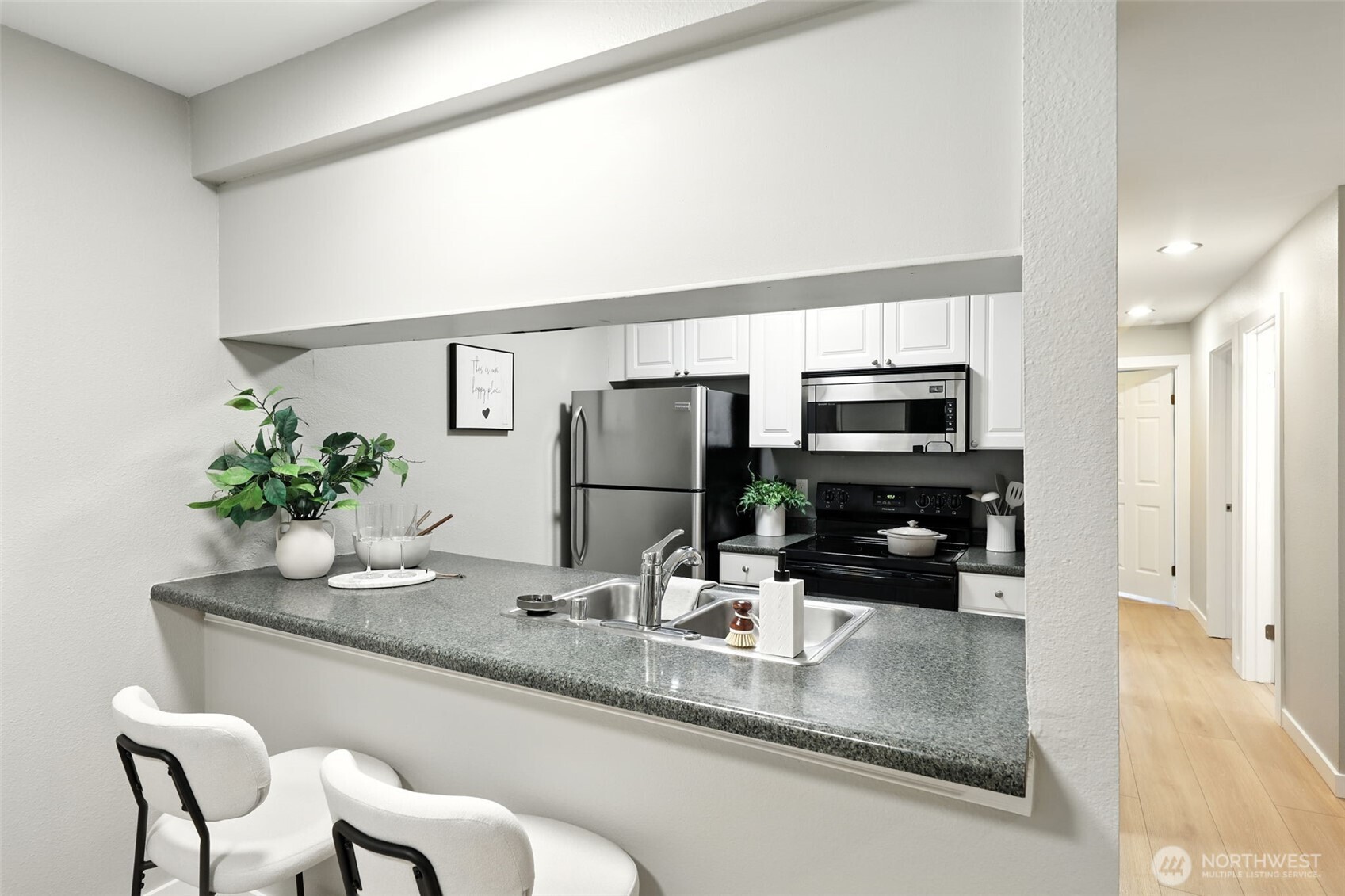 3233 Northeast 12th Street, Unit 207 Renton, WA 98056 - Photo 12 of 40 a kitchen with kitchen island granite countertop a sink and white cabinets