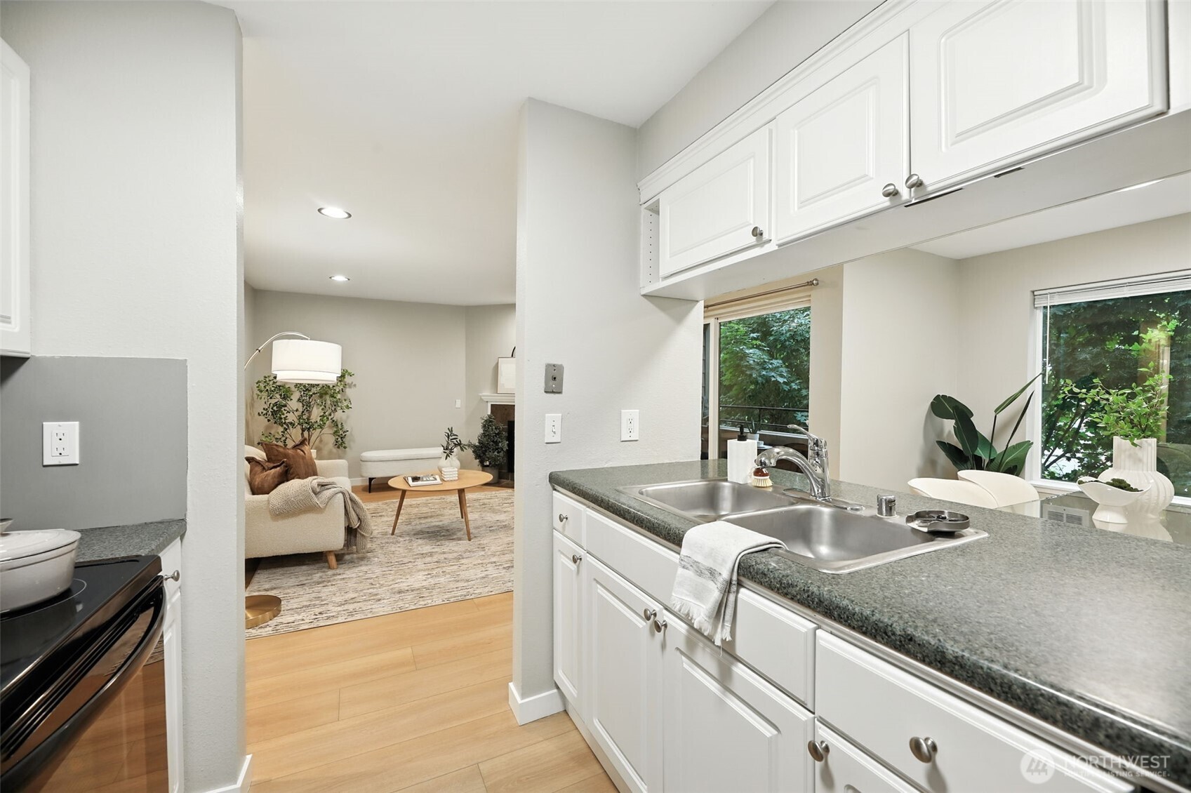 3233 Northeast 12th Street, Unit 207 Renton, WA 98056 - Photo 15 of 40 a kitchen with granite countertop a sink and white cabinets next to a window