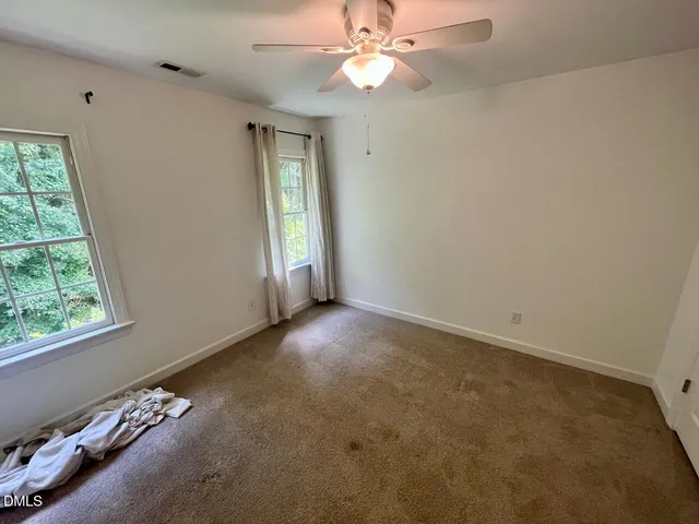 an empty room with windows and fan