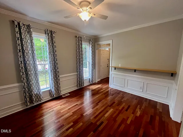 a view of empty room with wooden floor and fan