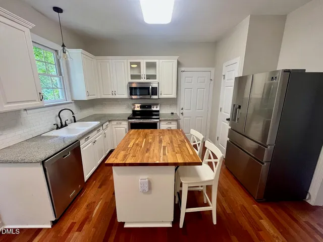 a kitchen with stainless steel appliances a refrigerator a sink a stove a table and chairs