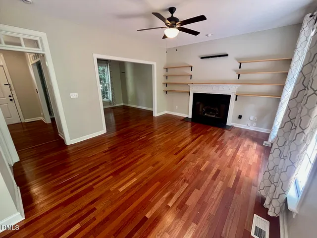 a view of empty room with wooden floor and fireplace