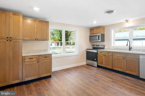 a kitchen with granite countertop white cabinets a sink a window and stainless steel appliances