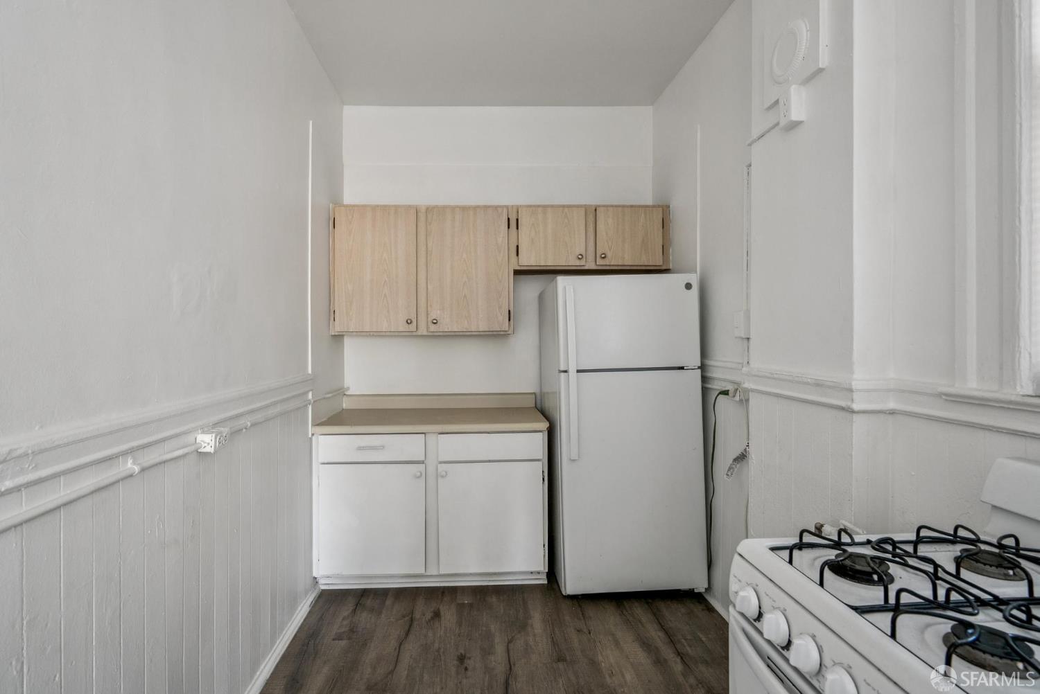 669 Ellis Street San Francisco, CA 94109 - Photo 16 of 32 a kitchen with a refrigerator a stove top oven and wooden floor