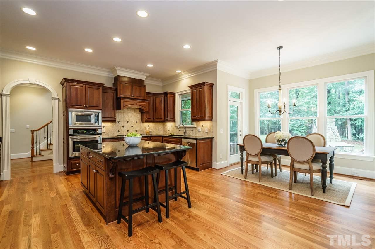 1801 Bowling Green Trail Raleigh, NC 27613 - Photo 9 of 25 a open kitchen with stainless steel appliances granite countertop a stove top oven a refrigerator a dining table and chairs with wooden floor