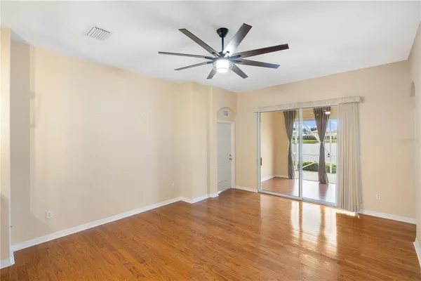 a view of an empty room with wooden floor and a window