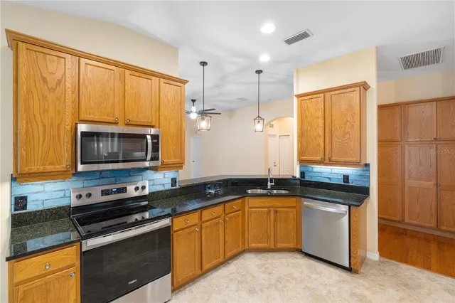 a kitchen with stainless steel appliances granite countertop a refrigerator and a stove top oven