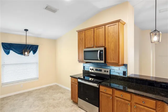 a kitchen with stainless steel appliances granite countertop a refrigerator a oven and white cabinets