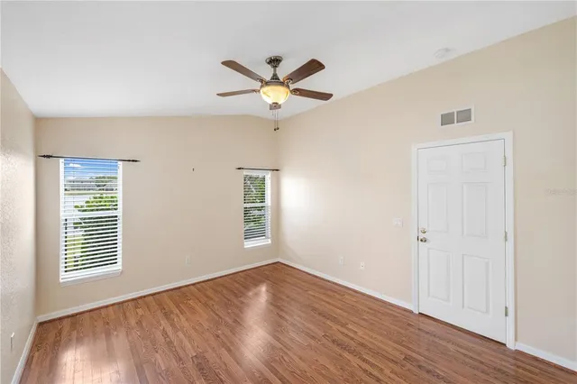 a view of a room with wooden floor and a ceiling fan