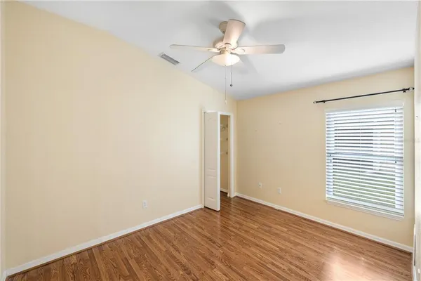an empty room with wooden floor fan and windows