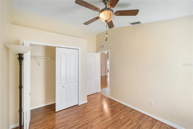 a view of empty room with wooden floor and ceiling fan
