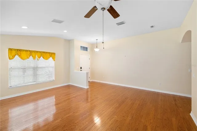 a view of an empty room with a window and wooden floor