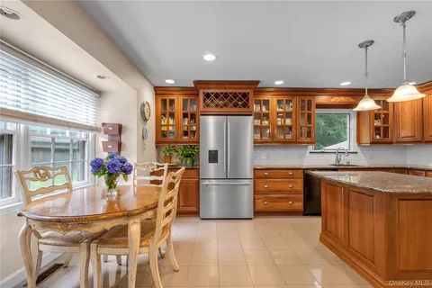 a kitchen with stainless steel appliances granite countertop a refrigerator a sink dishwasher and a dining table with wooden floor
