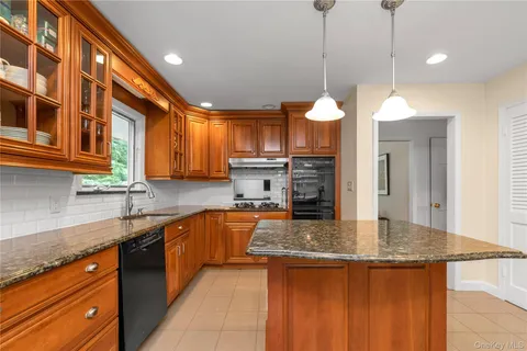 a kitchen with kitchen island granite countertop a sink a counter top space appliances and cabinets