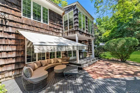 a view of a patio with couches and table and chairs with wooden floor and fence