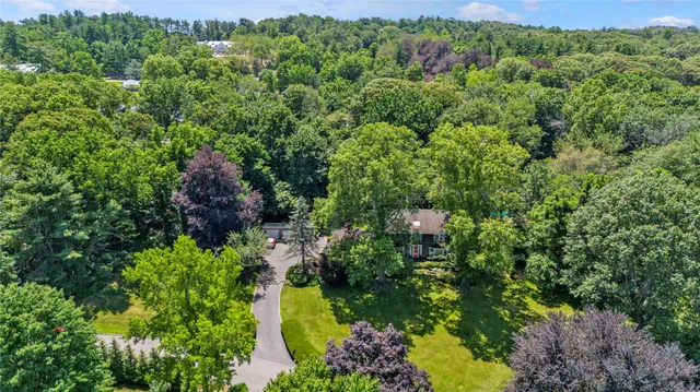 an aerial view of residential house with outdoor space and trees all around