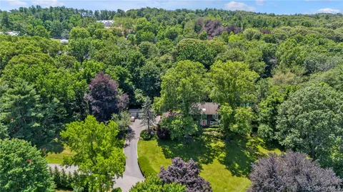 an aerial view of residential house with outdoor space and trees all around