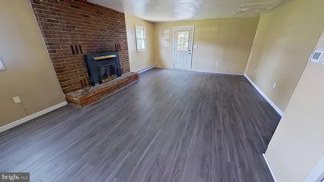 an empty room with wooden floor and fireplace