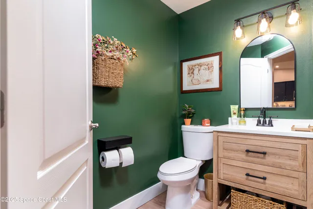 a bathroom with a toilet sink vanity and mirror