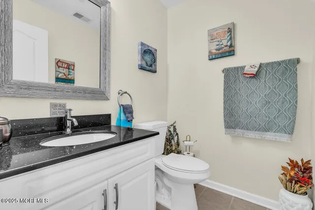a bathroom with a granite countertop sink mirror vanity and toilet