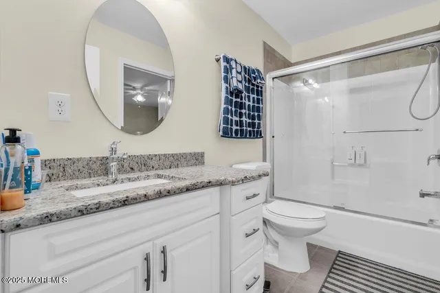 a bathroom with a granite countertop sink mirror vanity and toilet