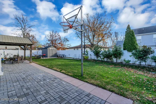 a view of a white house in front of a big yard plants and large trees