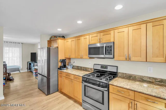 a kitchen with stainless steel appliances granite countertop a stove a sink dishwasher and a refrigerator with wooden floor