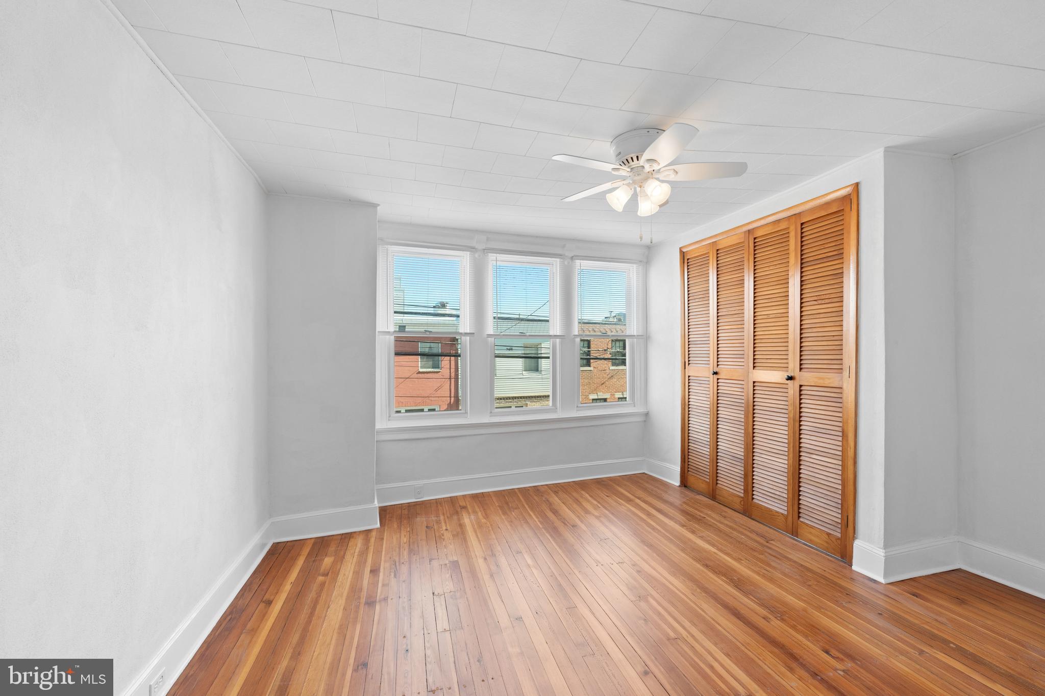 244 Mifflin Street Philadelphia, PA 19148 - Photo 9 of 21 an empty room with wooden floor chandelier fan and windows
