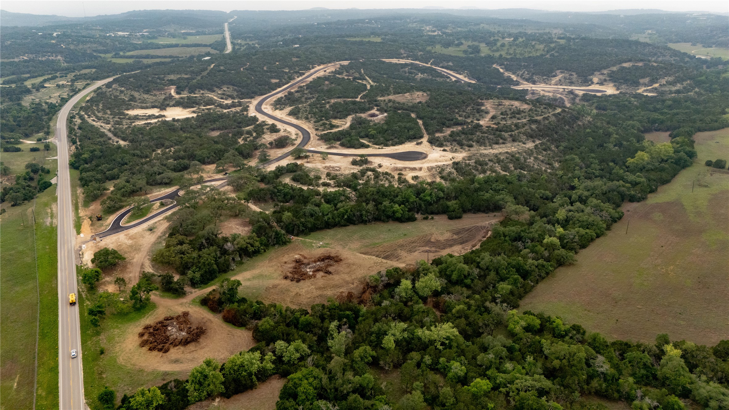 Lot 26 Ranch Road 165 Dripping Springs, TX 78620 - Photo 9 of 13 Expansive acreage showcasing undeveloped land with established roadways and a winding paved highway