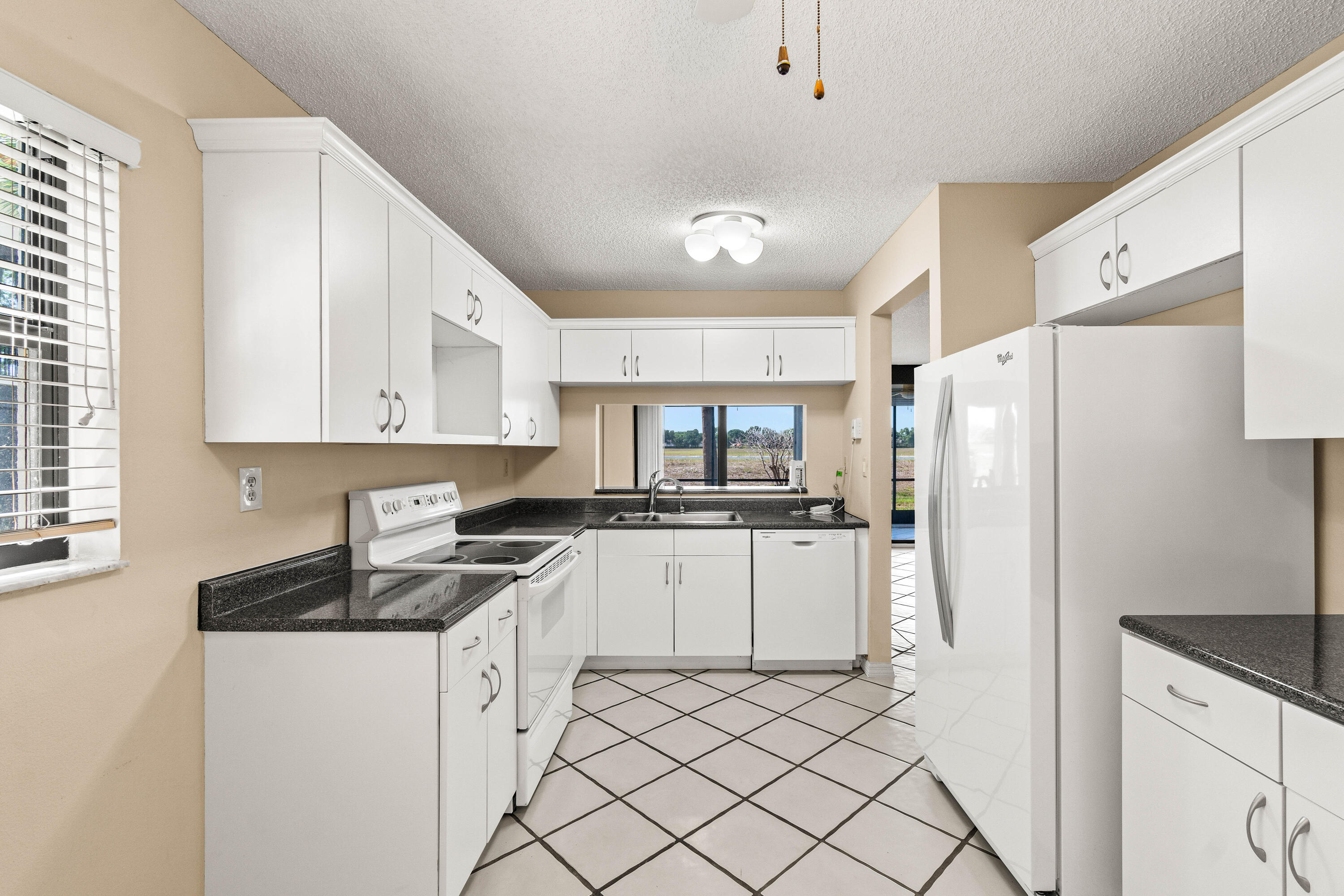 10920 Lakemore Lane, Unit 101 Boca Raton, FL 33498 - Photo 11 of 41 a kitchen with white cabinets and white appliances
