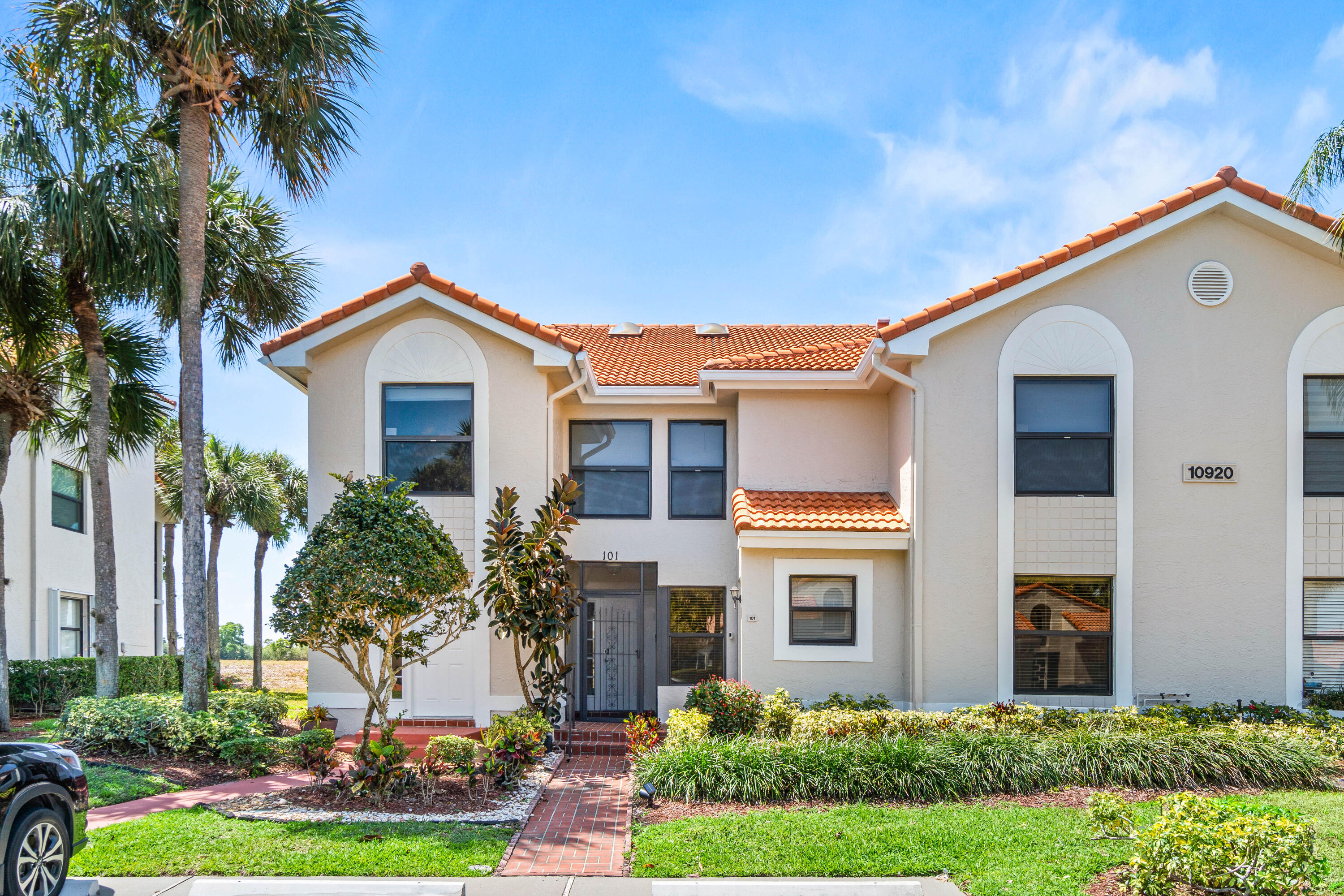 10920 Lakemore Lane, Unit 101 Boca Raton, FL 33498 - Photo 2 of 41 a front view of a house with a yard and potted plants