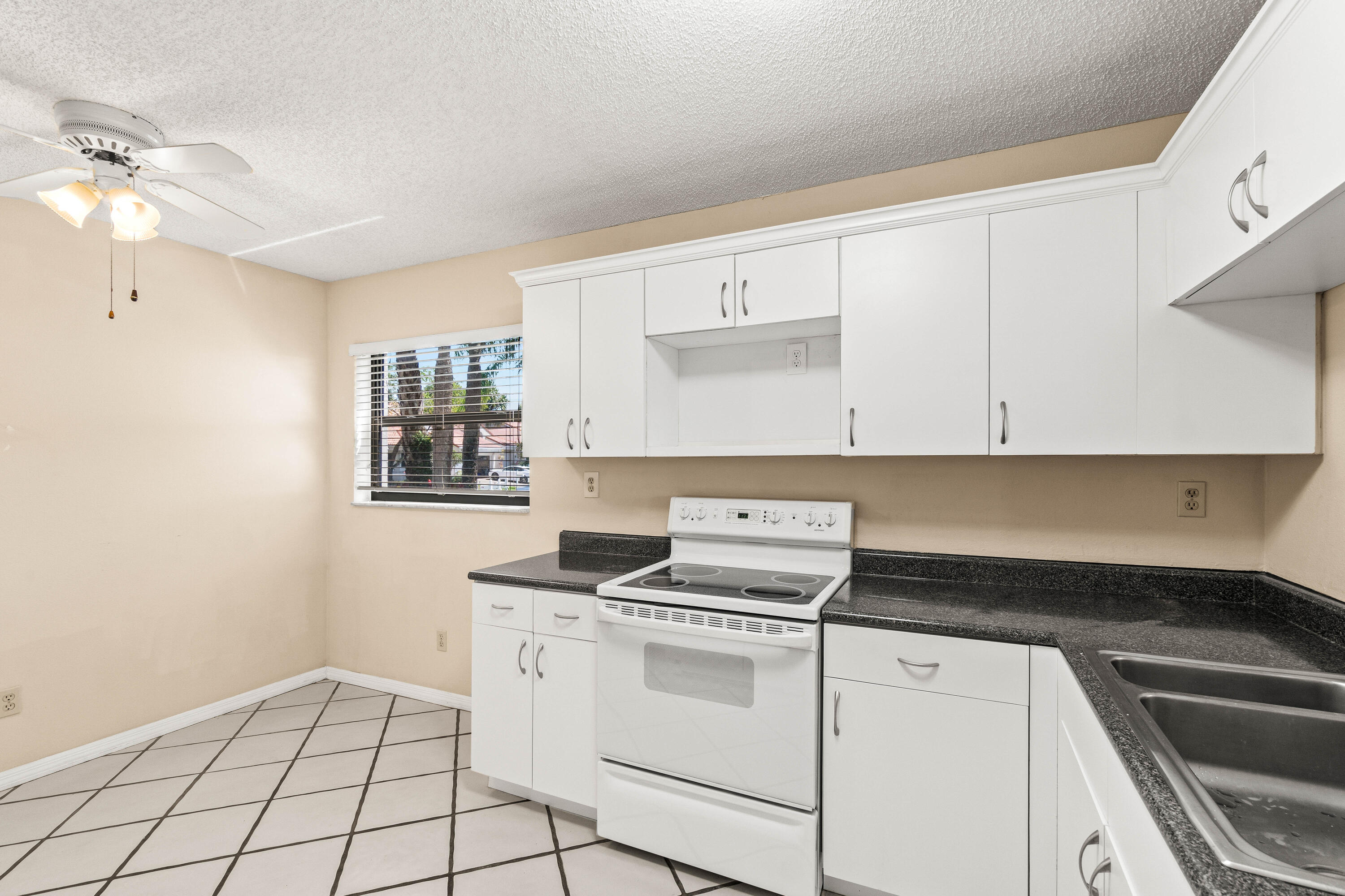 10920 Lakemore Lane, Unit 101 Boca Raton, FL 33498 - Photo 7 of 41 a kitchen with a stove cabinets and a sink