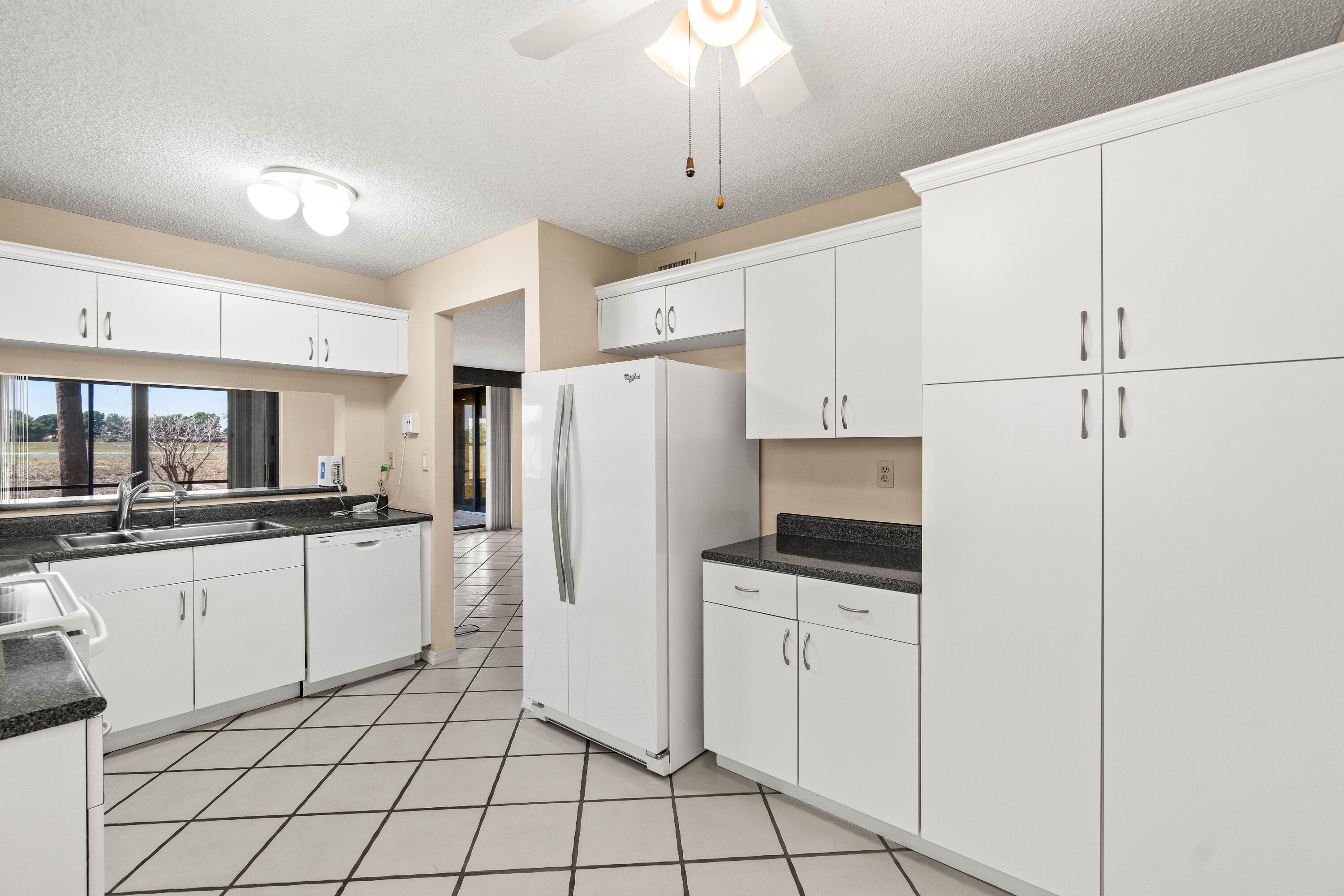 10920 Lakemore Lane, Unit 101 Boca Raton, FL 33498 - Photo 10 of 41 a kitchen with white cabinets and white appliances