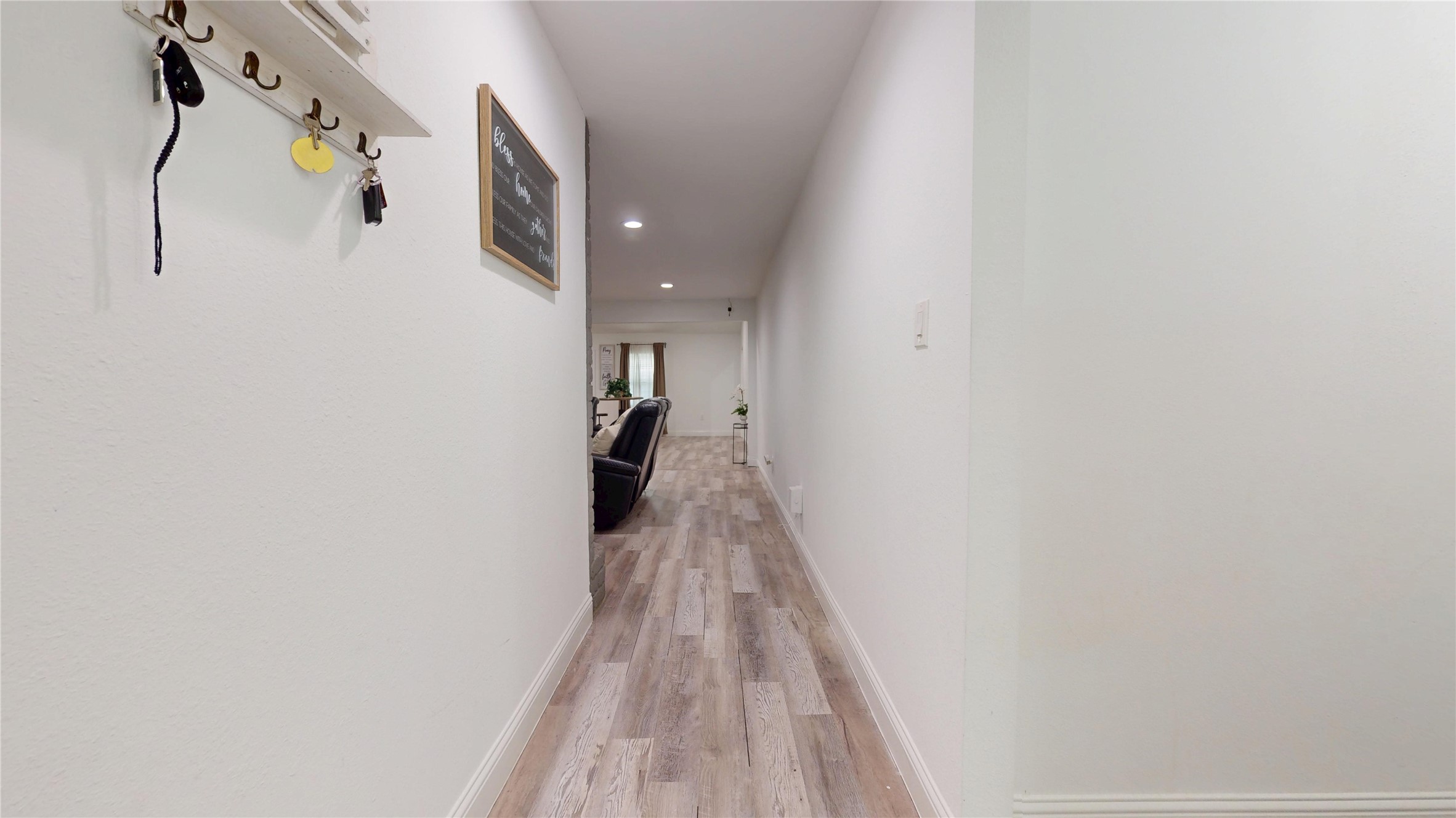 827 Dondell Street Channelview, TX 77530 - Photo 3 of 49 827 Dondell St, Hallway entry to living room area, with gray wooden laminate flooring throughout.