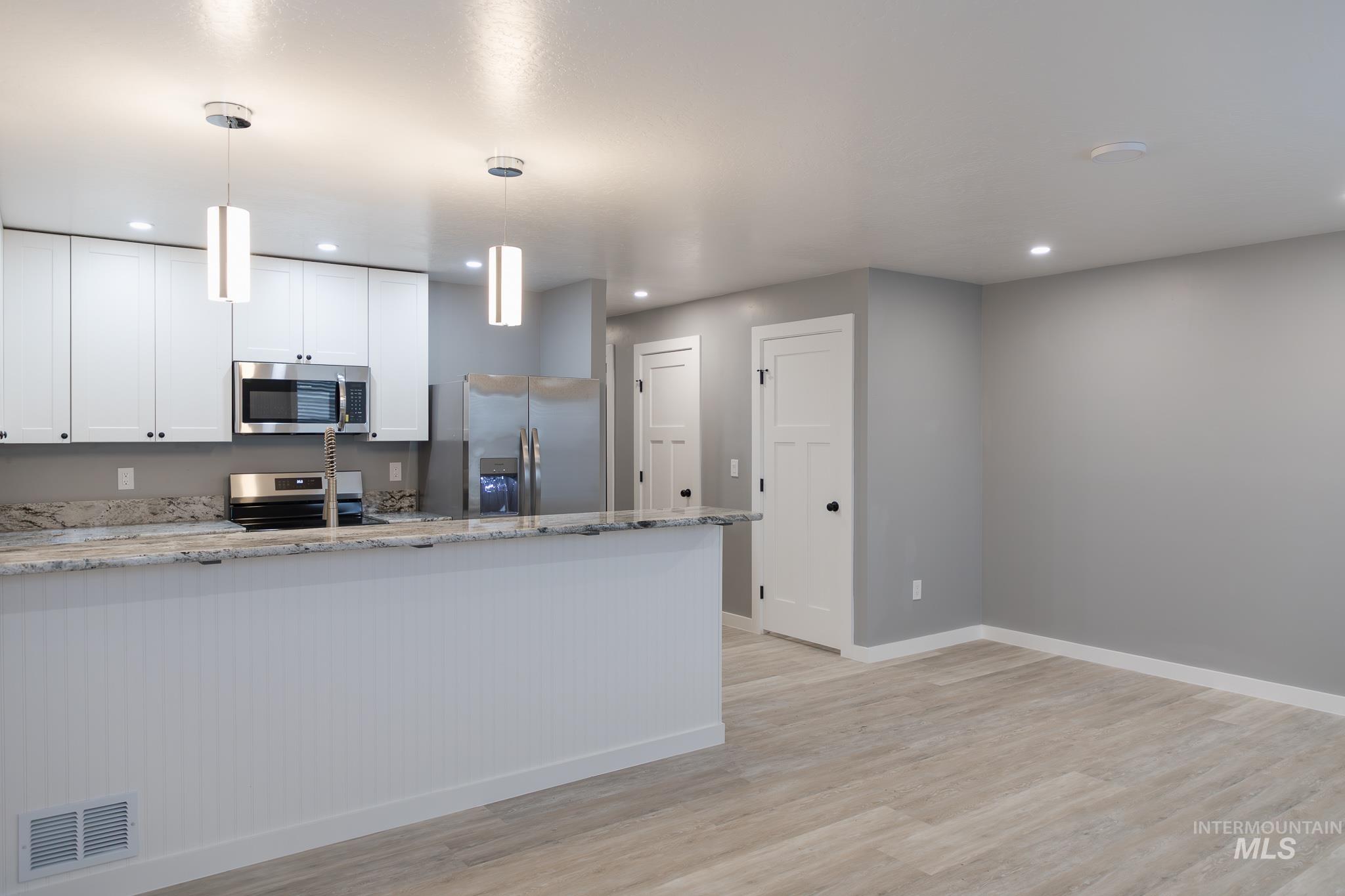 287 Southwest 6th Street, Unit 1 Ontario, OR 97914 - Photo 2 of 49 Kitchen featuring light stone counters, white cabinets, stainless steel appliances, and light wood-type flooring
